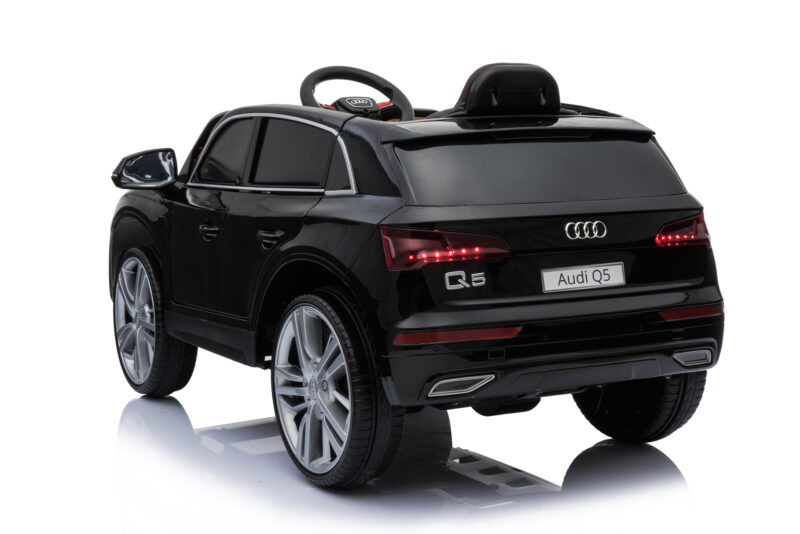Black Audi Q5 toy ride-on car, rear-right view with silver wheels and red taillights, reflective surface below.