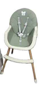 Green infant high chair with a five-point safety harness and light wood legs.