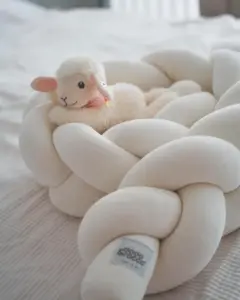 Small plush sheep nestled among smooth white pebbles in a soft, bright setting.