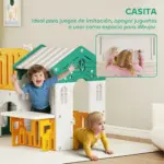 Dos niños pequeños juegan con un conjunto de juego grande de plástico colorido en una sala; parece un castillo o parque de actividades.