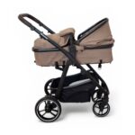Stroller with a tan bassinet, black frame, and a large under-seat storage basket in black fabric.