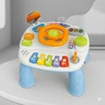 Colorful kids' activity toy with a orange steering wheel, large buttons, and a small mirror on top, set on blue legs.