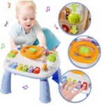 Baby playing with a colorful activity table featuring buttons, a steering wheel, and musical notes.