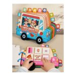 Bright, multi-page children's Busy Book shaped like a blue delivery truck with numbered tabs on the side; hands interact with the pages showing food icons.