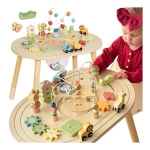 Baby in a red shirt plays with a two‑tier wooden activity table filled with colorful beads, gears, and wooden toy cars.