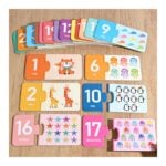 Colorful wooden number puzzle pieces arranged on a wooden floor, showing numbers 1–17 with pictures and words for each number.