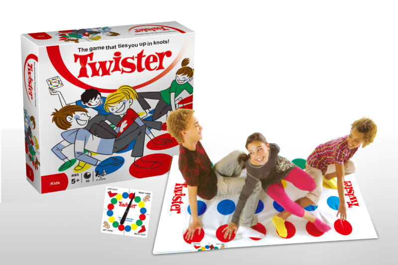 Twister game box with colorful cartoon players and a white background, showing the red Twister logo and the slogan "The game that ties you up in knots!"