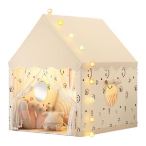 Cream-colored children's play tent shaped like a house with string lights, scalloped trim, and sheer curtains inside a cozy interior.