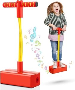 Child stands on a red pogo-stick toy with a yellow spring and T-bar handle, cheerful and ready to bounce.