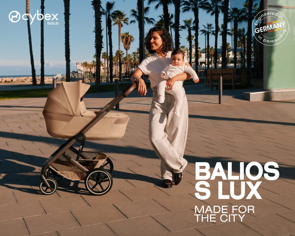 Mother carries a baby in a beige stroller along a palm-lined promenade by the beach; Cybex Gold branding visible on the left.