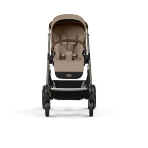 Front view of a beige baby stroller with four wheels, canopy, and a brown handlebar. Reversible seat and storage basket beneath.