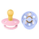 Pair of baby pacifiers: pink with yellow nipple on left, blue with cartoon design on right (set of two).